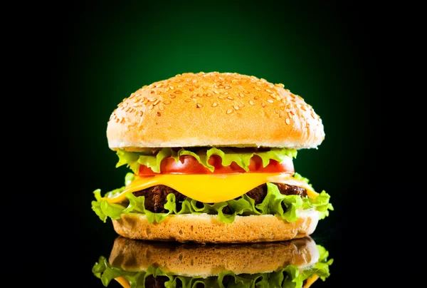 Tasty hamburger and french fries on a dark — Stock Photo, Image