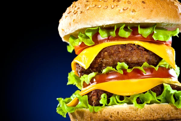 Tasty and appetizing hamburger on a dark blue — Stock Photo, Image
