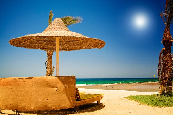 Palme, Sonnenschirm und Meer gegen blauen Himmel. — Stockfoto