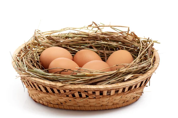 Chicken eggs and hay in the brown basket . — Stock Photo, Image