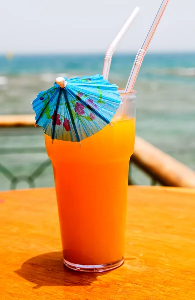 Tasty cocktail with paper umbrella against Red Sea. — Stock Photo, Image