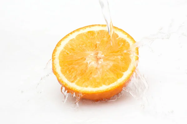 Wasser spritzt auf die Hälfte der reifen, saftigen Orange. — Stockfoto