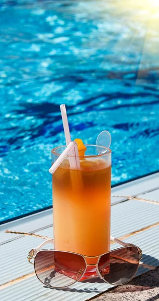 Sunglass and tasty cocktail with lemon next to swimming pool. — Stock Photo, Image