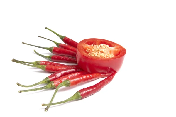 One red half and several whole peppers on a white. — Stock Photo, Image