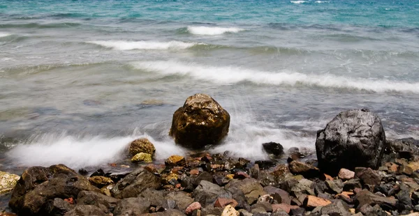 Meeresschaum und Kieselsteine im Wasser. — Stockfoto