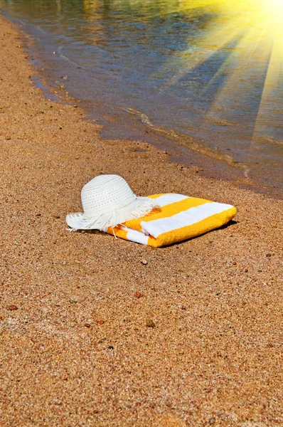 Türkisfarbenes Meer, Sonnenhut und Handtuch. — Stockfoto