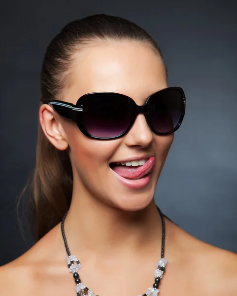 Девушка в солнечных очках показывает свой язык — стоковое фото