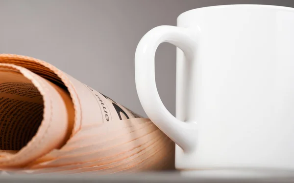 Cup and folded newspaper — Stock Photo, Image