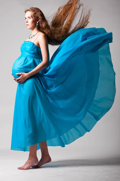 Беременная женщина с летающим платьем — стоковое фото