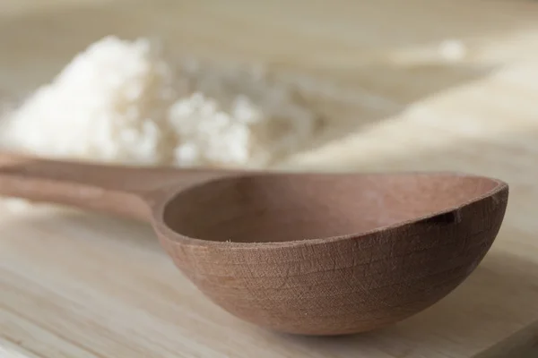 Rice grains and empty wooden spoon — Stok Foto