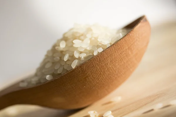 Rice grains in a wooden spoon — Stock Photo, Image
