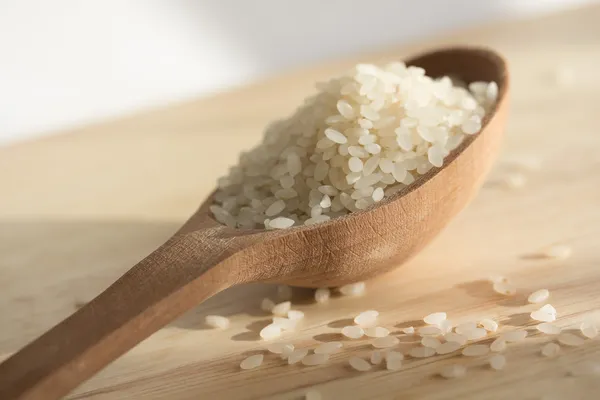 Granos de arroz en una cuchara de madera Imagen De Stock
