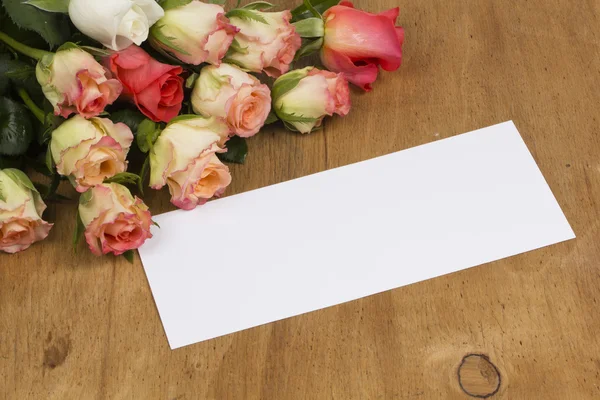 Card and roses on a wooden background — Stock Photo, Image