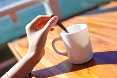 Young woman stir tea in cup clipart