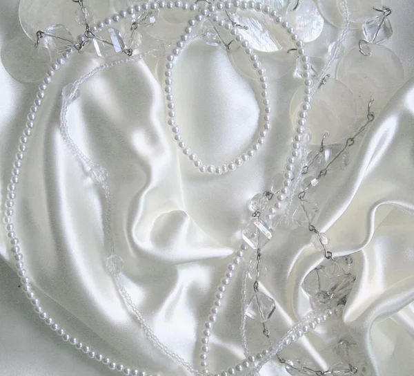 Weiße Perlen und Nagelbeeren auf weißer Seide — Stockfoto