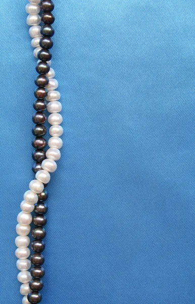 stock image Pearls on the smooth elegant blue silk as background