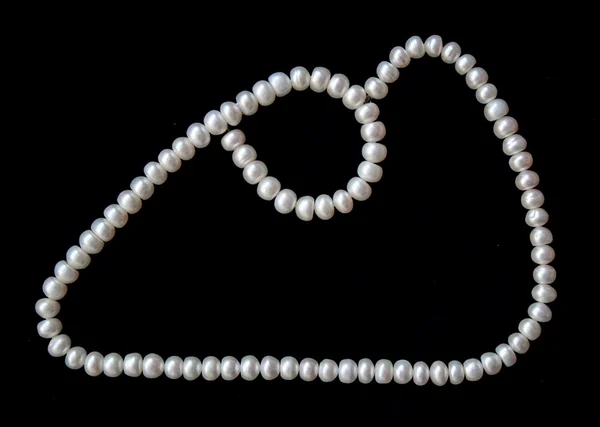 Білі перлини на чорному шовку як фон — стокове фото