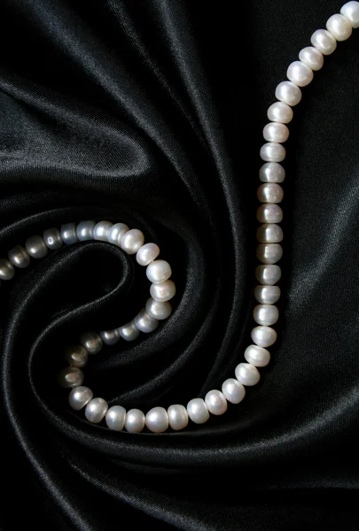 Vita pärlor i svart siden bakgrunden — Stockfoto