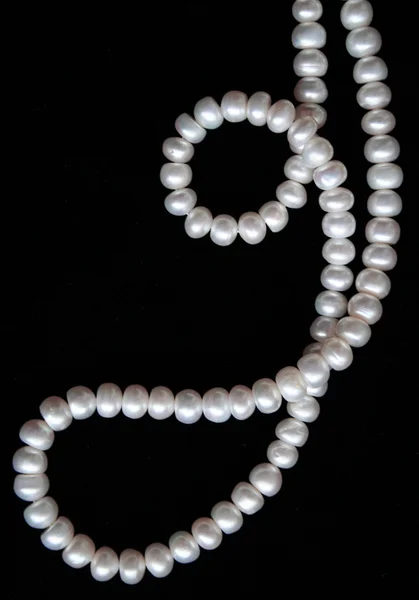 Vita pärlor på svart silke som bakgrund — Stockfoto