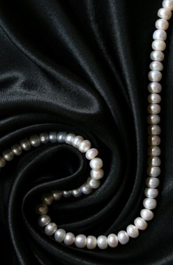 White pearls on the black silk as background clipart