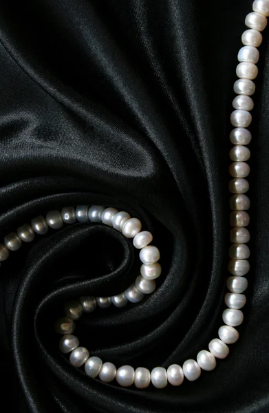 Pérolas brancas na seda preta como fundo — Fotografia de Stock