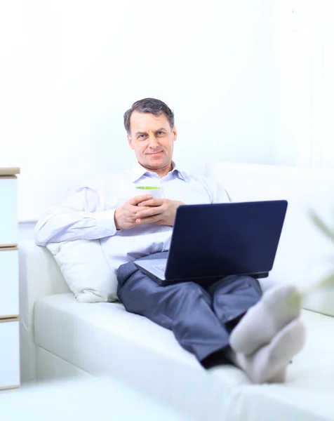 Empreendedor trabalhando em casa olhando muito relaxado em seu sofá navegando th — Fotografia de Stock