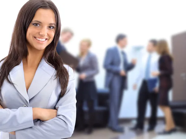 Mulher de negócios bem sucedida de pé com seu pessoal no fundo no escritório — Fotografia de Stock