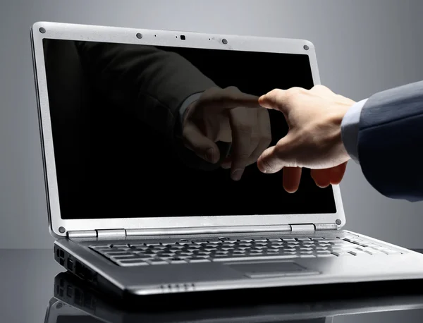 Bliska męskiej dłoni z palcem wskazującym, wskazując na ekranie laptopa na czarno — Zdjęcie stockowe