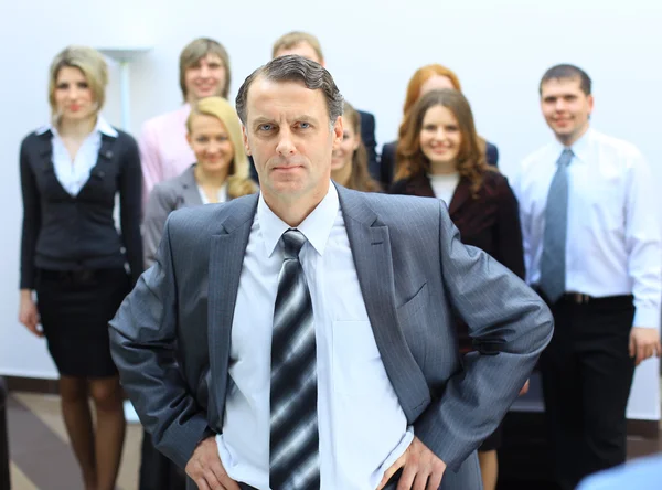 Homem de negócios no escritório com um grupo atrás dele — Fotografia de Stock