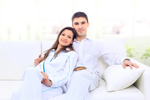 Portrait of a lovely young couple sitting together on couch at home - Indoo — Stock Photo, Image
