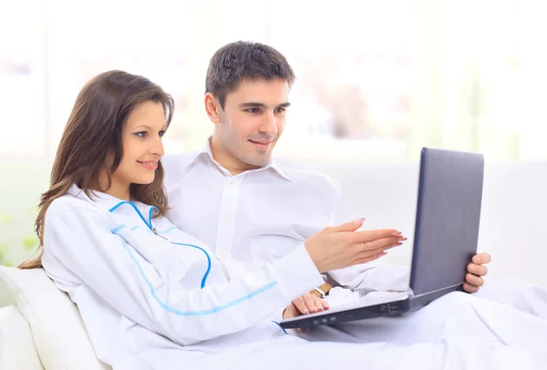 Portret szczęśliwy młoda para siedzi na kanapie przy użyciu laptopa — Zdjęcie stockowe