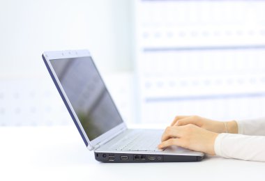 Person Typing on a modern laptop in an office clipart