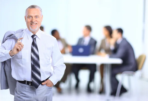 Erfolgreicher Geschäftsmann steht mit seinen Mitarbeitern im Hintergrund im Büro — Stockfoto