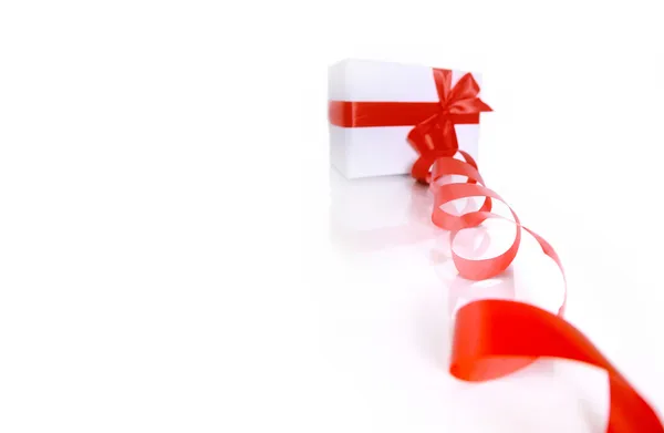 Cadeau enveloppé avec un ruban rouge sur un fond blanc — Photo
