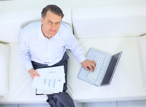 Empresário sênior sentado no sofá e usando laptop — Fotografia de Stock