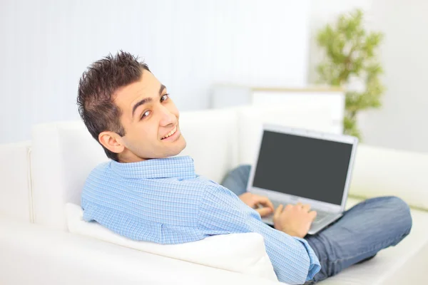 Retrato de un hombre que se relaja en el sofá mientras usa una computadora portátil — Foto de Stock