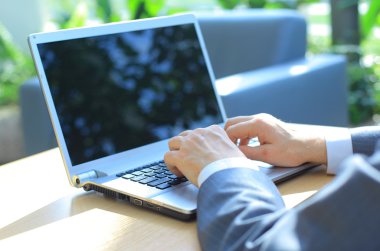 Person Typing on a modern laptop in an office clipart