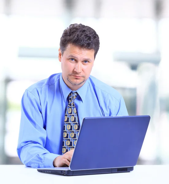 Бизнесмен, работающий за ноутбуком в офисном холле — стоковое фото
