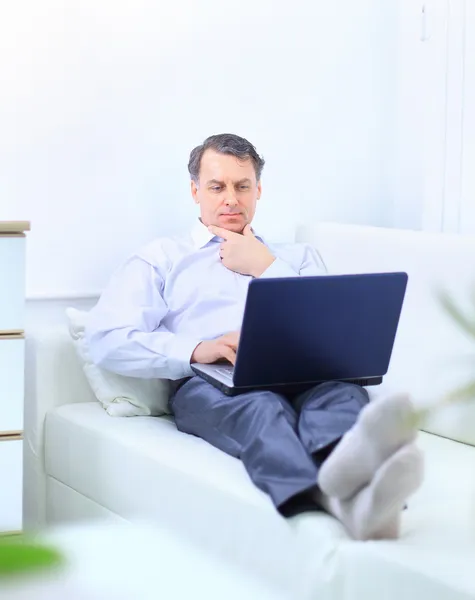 Предприниматель работает из дома выглядит очень расслабленным в своем диване просмотра й — стоковое фото