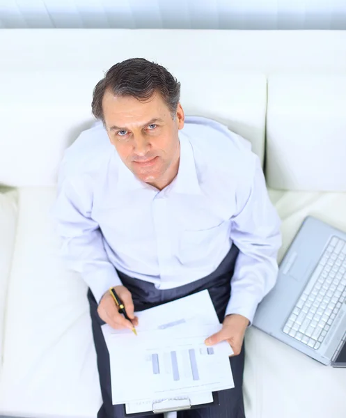 Empresário sênior sentado no sofá e usando laptop — Fotografia de Stock