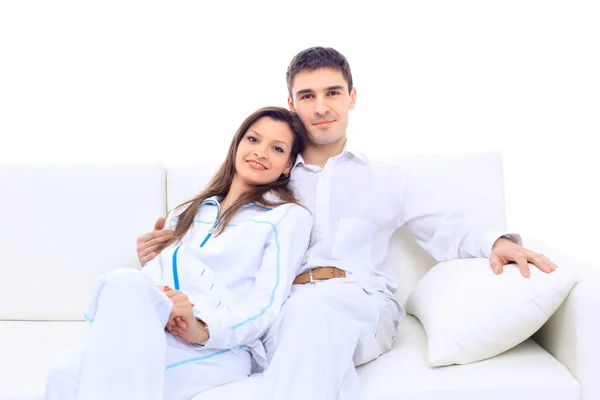 Unga söta Europeiska par om en vit soffa - isolerade över vita. — Stockfoto