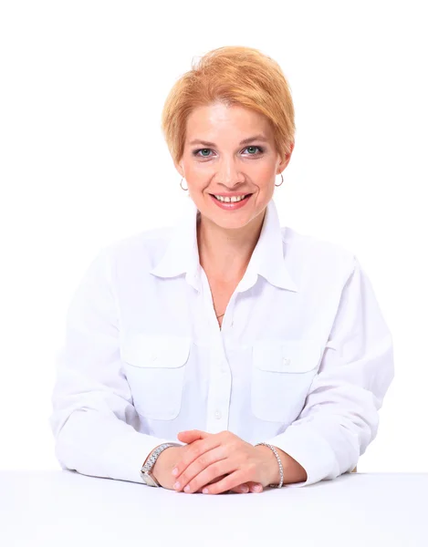 Blond kobieta uśmiechający się siedzi przy biurku na białym tle na biały deseń — Zdjęcie stockowe