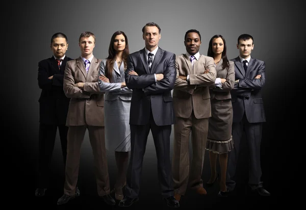 Business team formed of young businessmen standing over a dark background — Stock Photo, Image