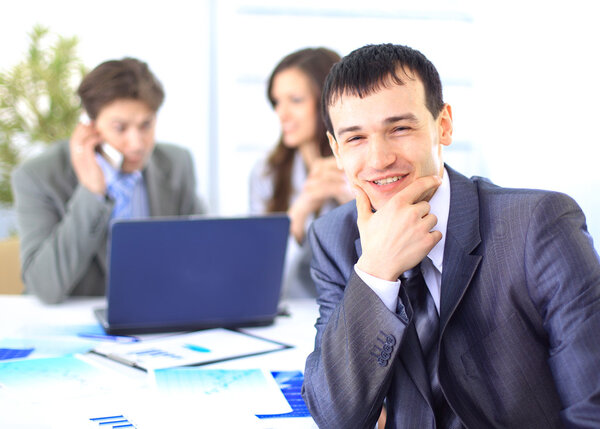 Smiling satisfied businessman looking at camera with his colleagues in the