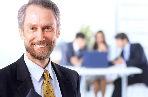 Hombre de negocios exitoso de pie con su personal en segundo plano en la oficina —  Fotos de Stock