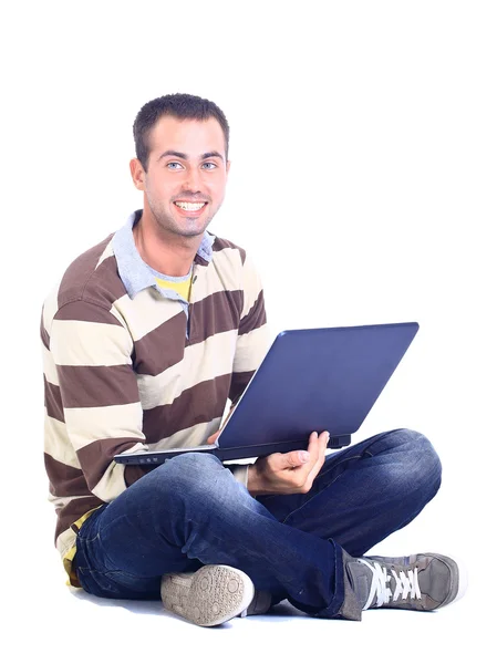 Genç adam oturmuş ve bir dizüstü bilgisayar kullanarak — Stok fotoğraf