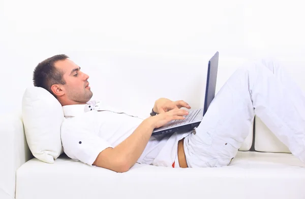 Uomo felice che lavora sul suo computer portatile sul divano di casa — Foto Stock