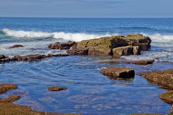 Golven die breken againt rotsachtige kust — Stockfoto