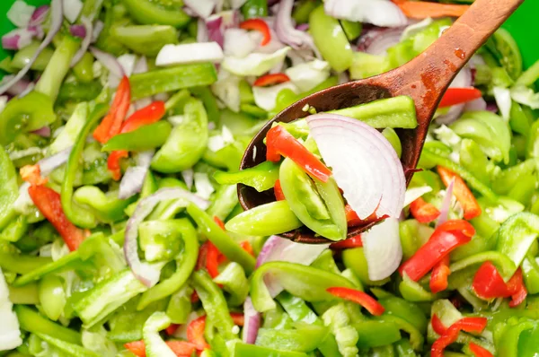 Tahta kaşık üzerinde yeşil domates, biber ve soğan salata — Stok fotoğraf