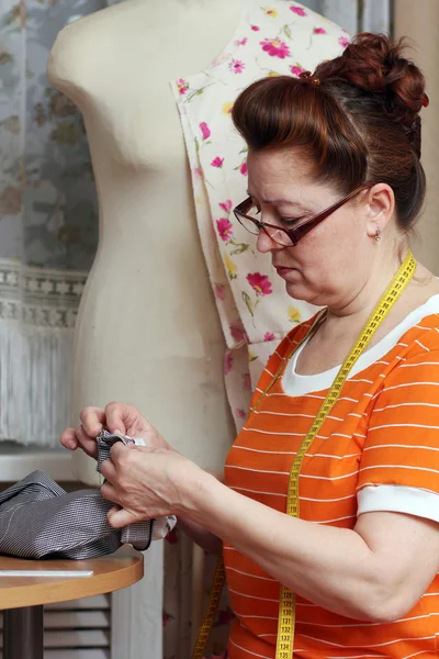 Oude vrouw naait kleren in-home — Stockfoto